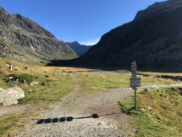 Vista in primo piano di un pannello con indicazioni e in secondo piano una distesa di montagne