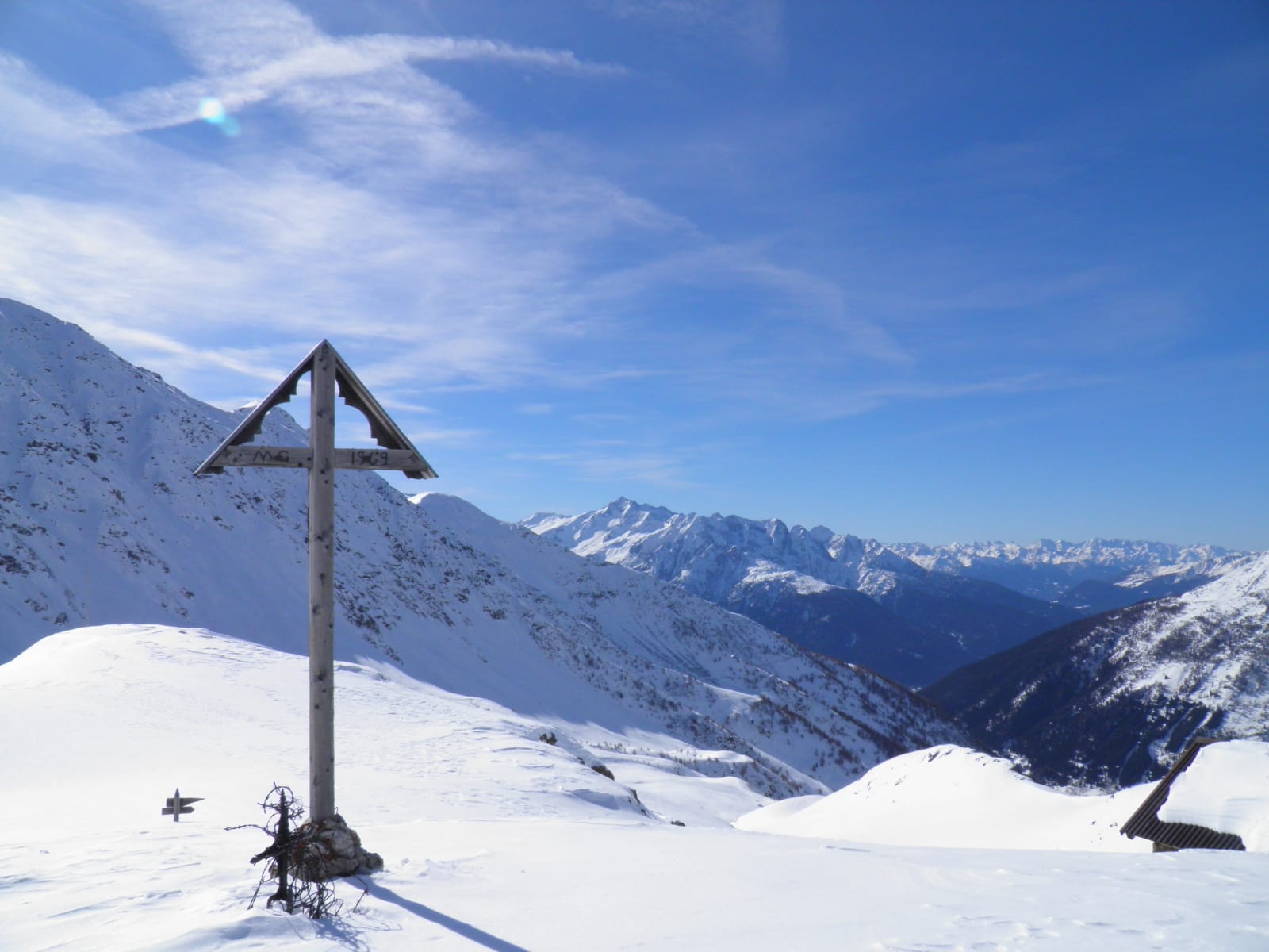 Foto di un palo indicativo in mezzo alla neve e alle montagne altrettanto ricoperte di neve