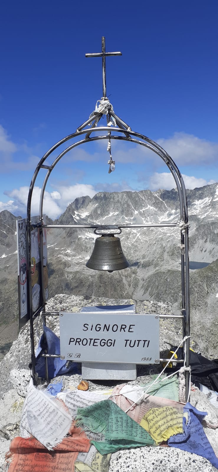 Foto della Cima Plem con un campanello, piccole bandierine e la croce