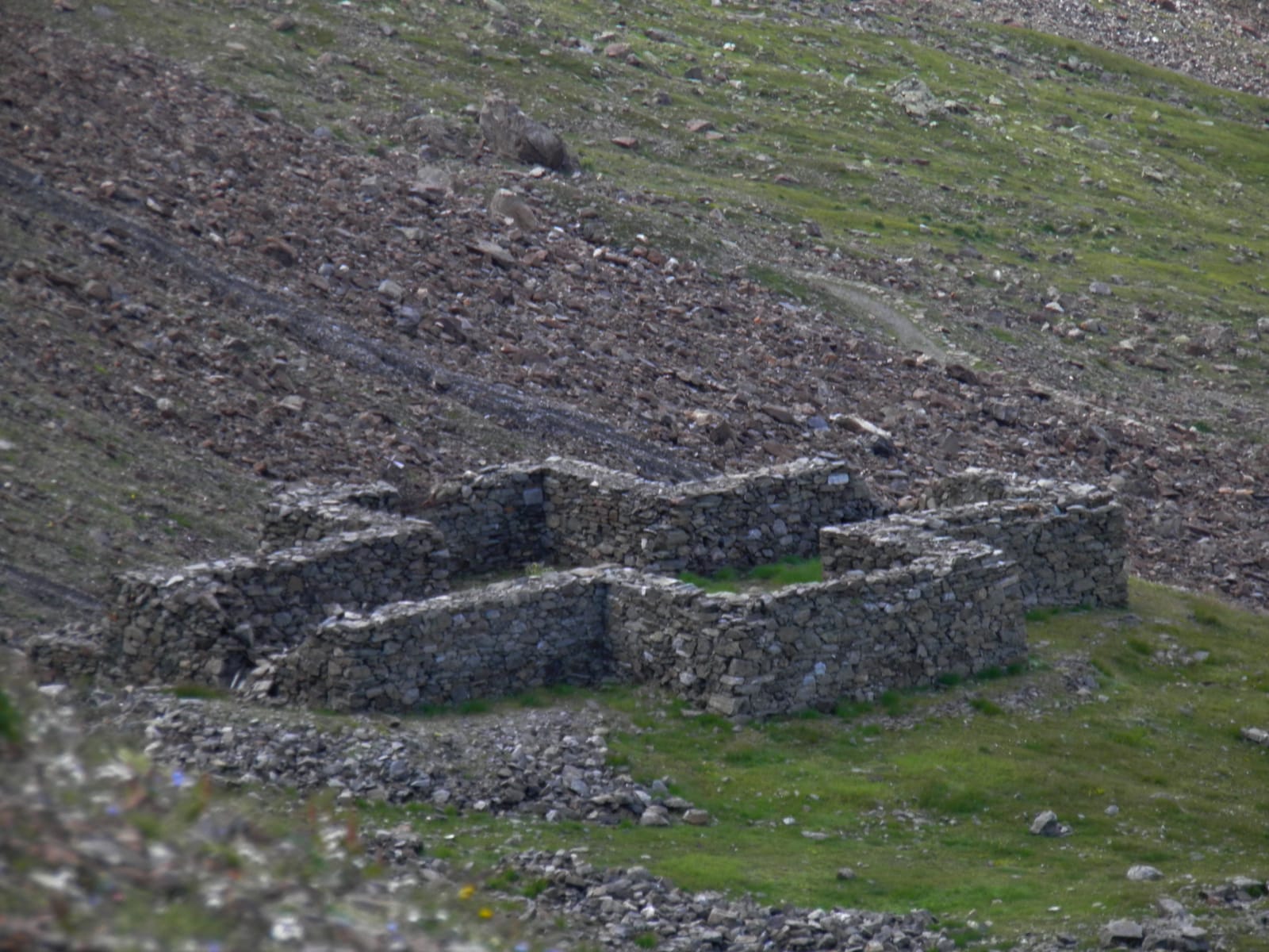 Foto di una costruzione fatta di muraglie in roccia circondato dal verde e altre rocce