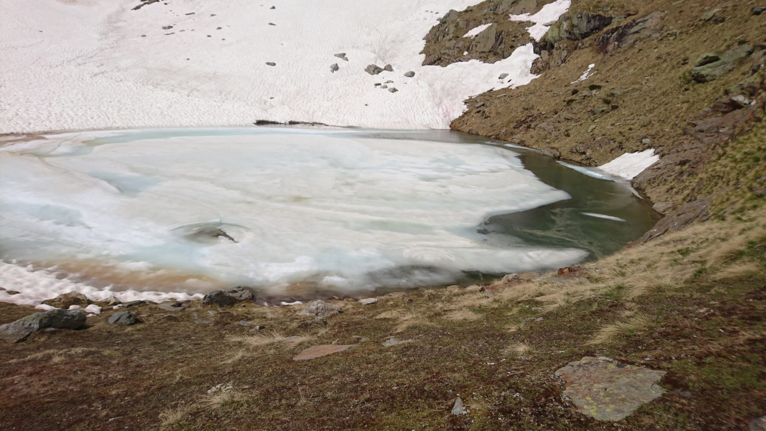 Vista di uno stagno ghiacciato in mezzo alle montagne coperte di neve