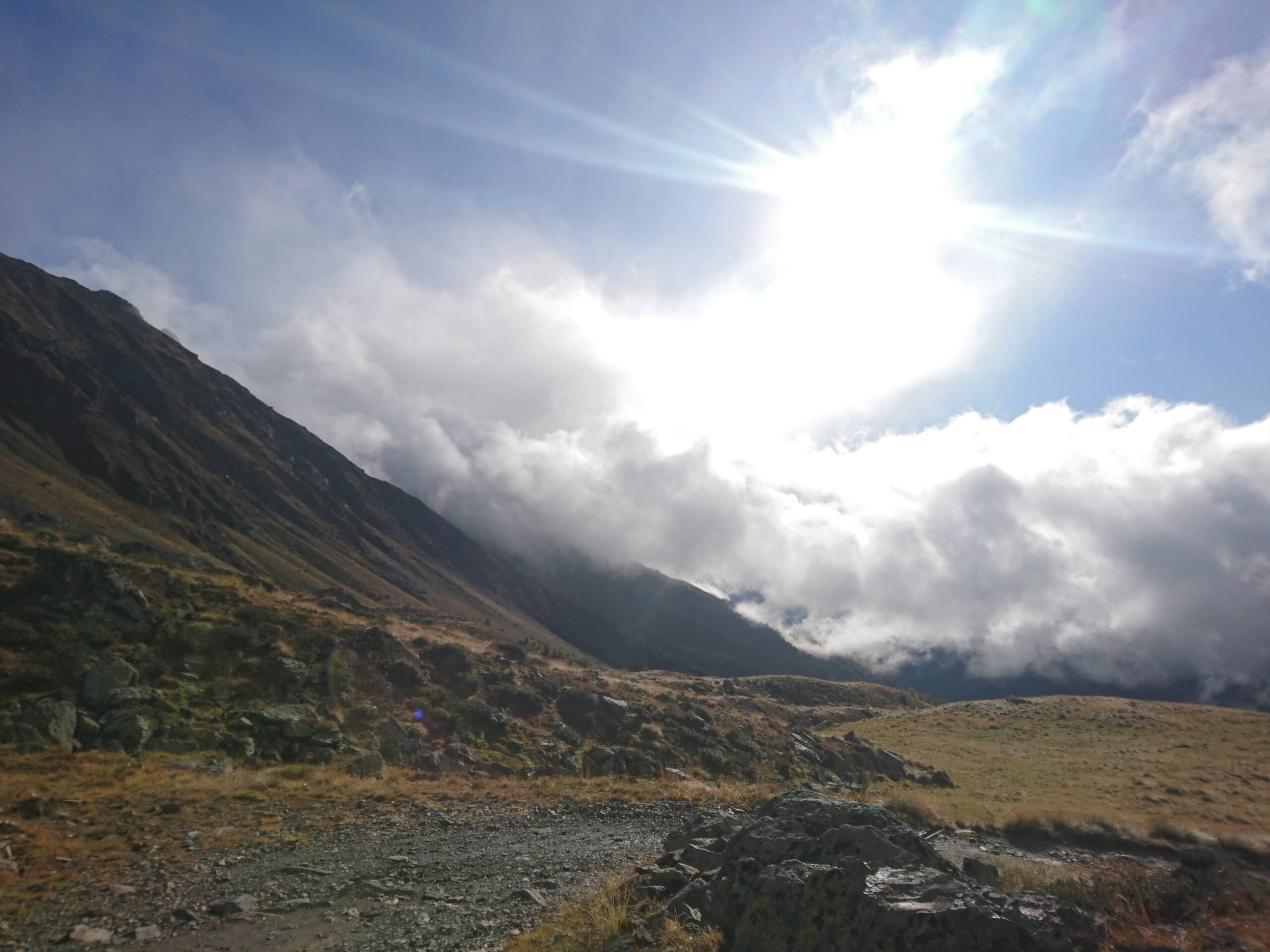 Vista montagna ed un solo splendente su un cielo limpido e con piccole nuvole