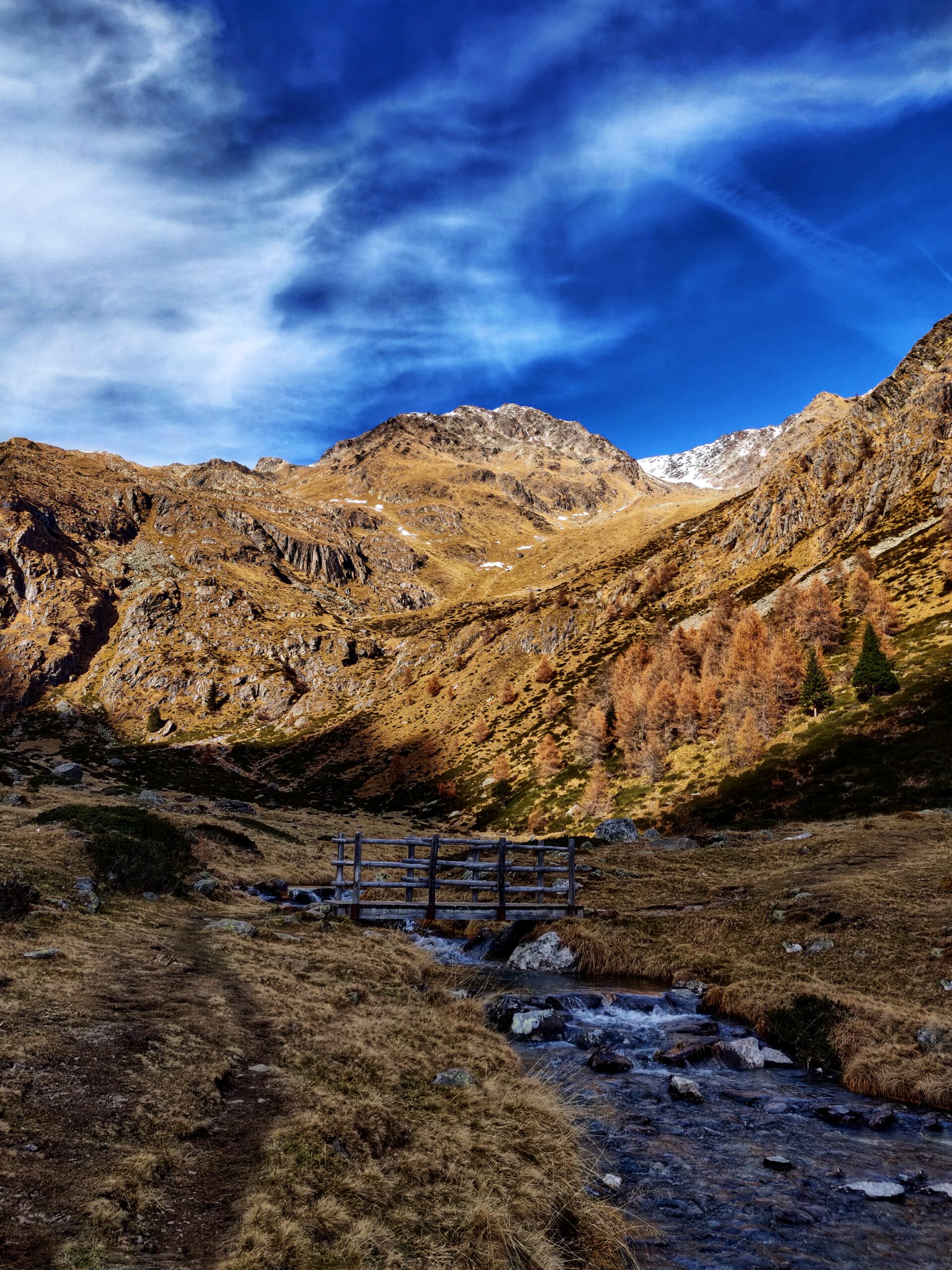 Vista di un piccolo sentiero d'acqua con un piccolo ponte da attraversare per raggiungere le montagne da entrambi i lati