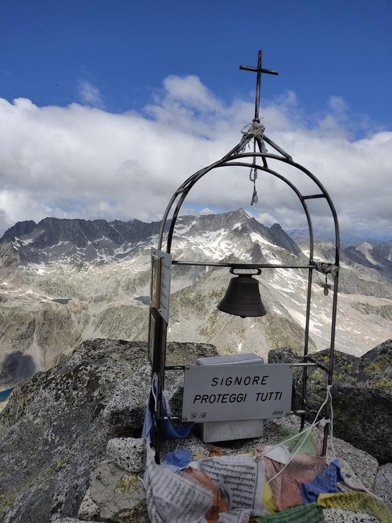 Foto della Cima Plem con un campanello, piccole bandierine e la croce